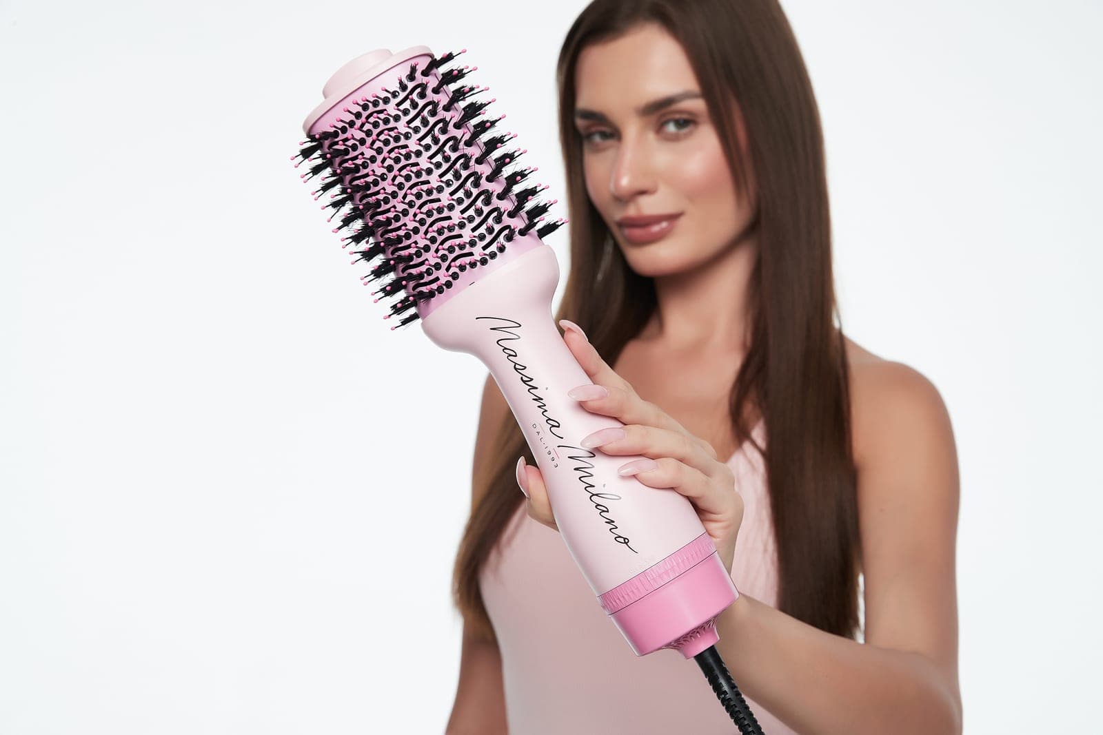 A model holds the pink Massima Milano MAGNA 3-in-1 hot air styling brush toward the camera.